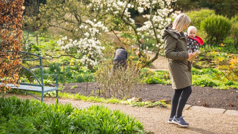 A mother holds a baby while walking the garden